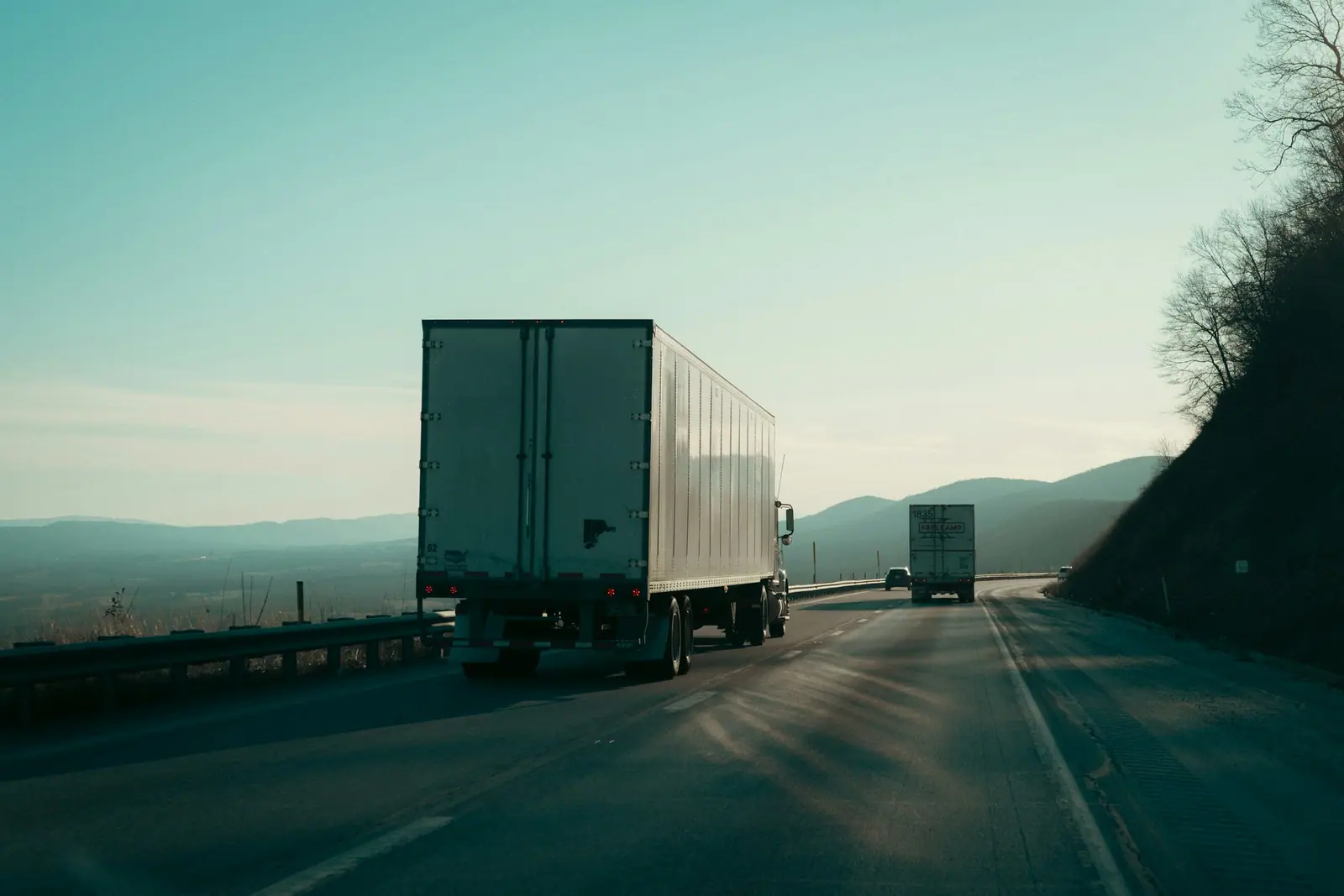 Two semi-trailer trucks on a highway